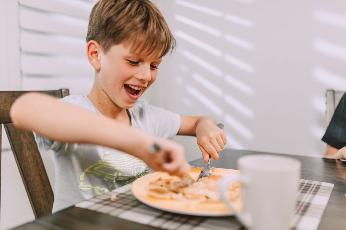 Un enfant heureux à table devant son assiette
