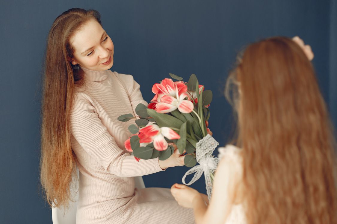 Une petite fille qui offre des fleurs à sa maman