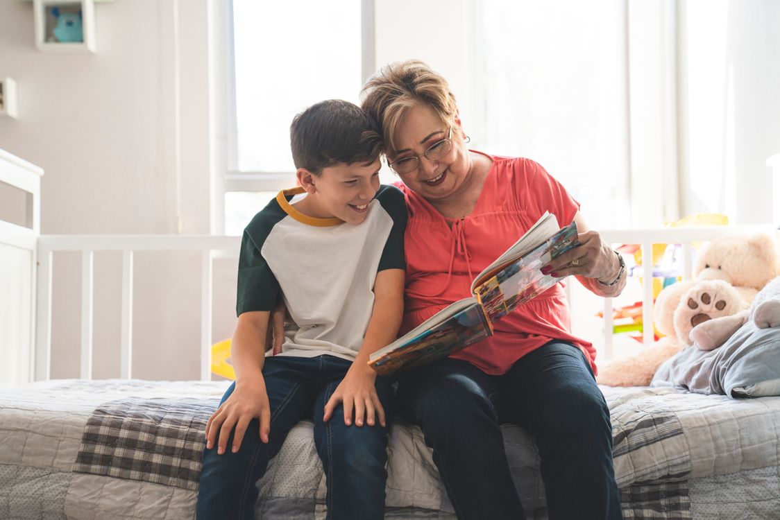 Une grand-mère lit un livre d'images à voix haute avec son petit-fils installé contre elle