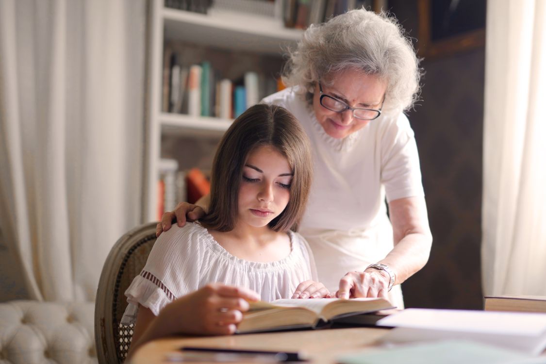 Une grand-mère et sa petite-fille penchées ensemble sur les pages d'un album illustré