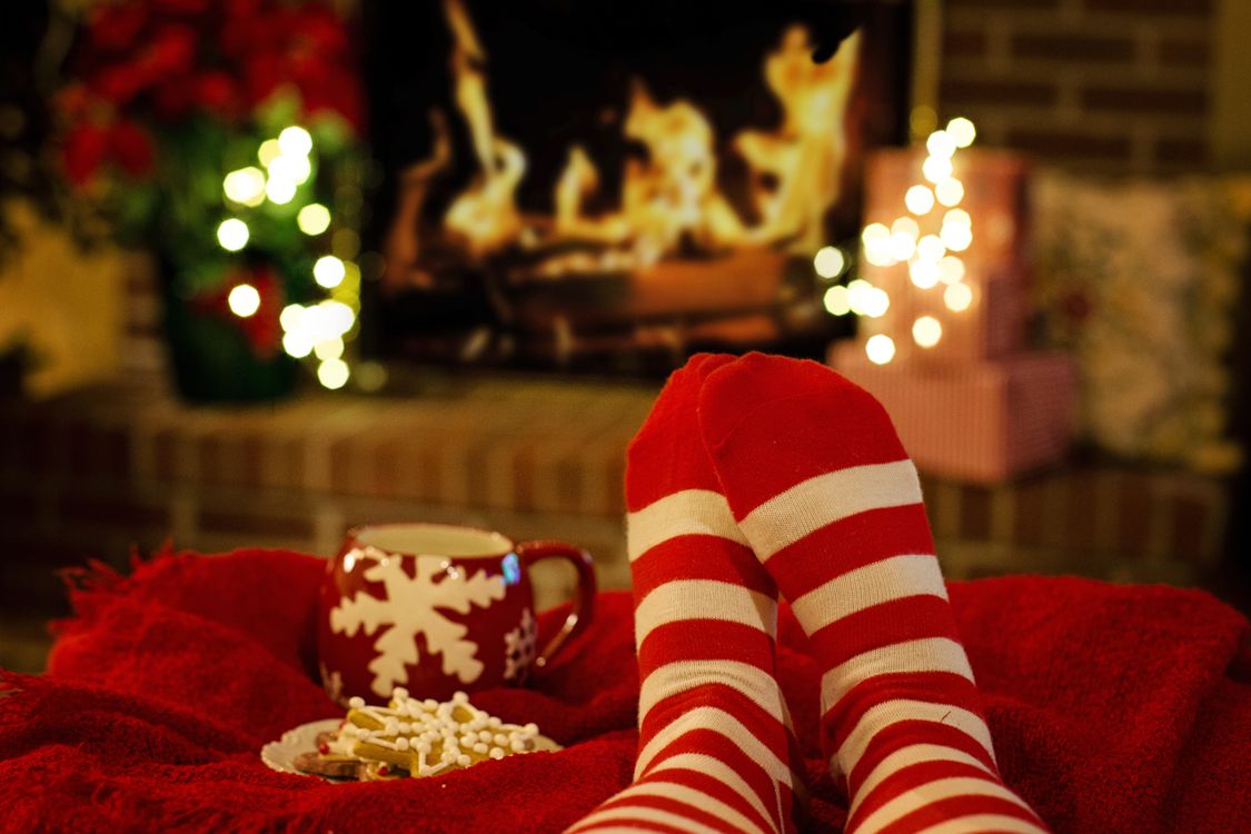 Des chaussettes suspendues près d'une cheminée, avec une tasse et des biscuits posés à côté