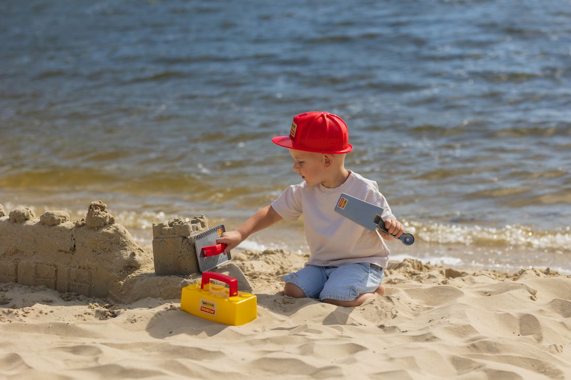 Petit garçon construisant un château de sable sur la plage, un souvenir de vacances classique à revivre ensemble