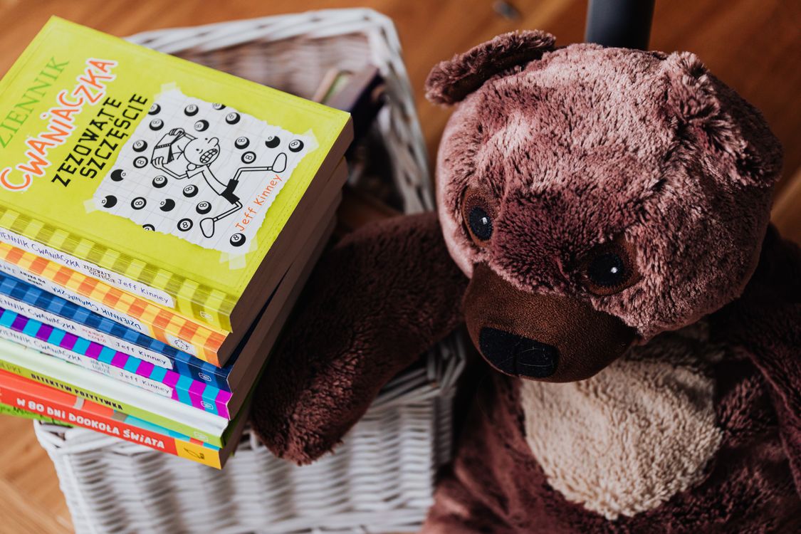 Pile de livres illustrés colorés à côté d'un ours en peluche dans une chambre d'enfant