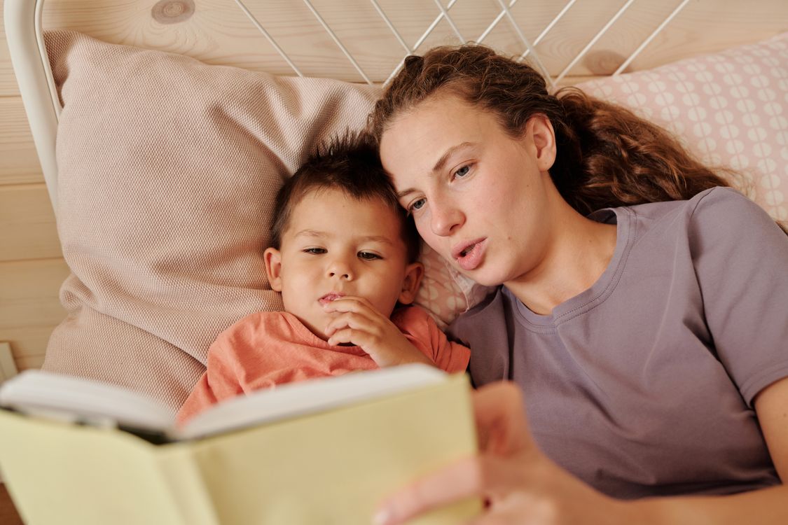 Un parent lit une histoire du soir familière à son enfant dans une chambre douillette